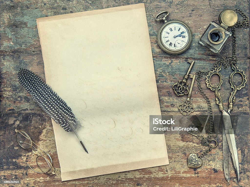 Letter paper with vintage writing tools. Feather pen and inkwell Letter paper and vintage writing tools. Feather pen, inkwell, keys on textured wooden background. Retro style toned picture 2015 Stock Photo