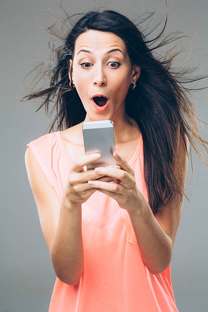 Fast Internet A girl holding a smart phone amazed by her powerful internet. mouth open human face shouting screaming stock pictures, royalty-free photos & images