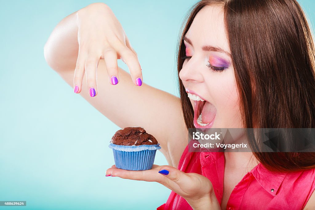 Smiling woman holds chocolate cake in hand Sweet food sugar make us happy. Smiling woman holds cake chocolate muffin in hand blue background 2015 Stock Photo