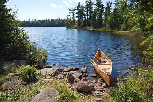 A yellow fisherman's canoe on a rocky shore of a northern Minnesota lake