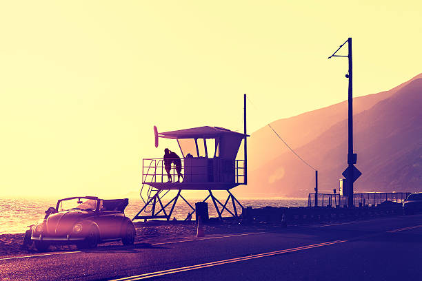 Vintage filtered sunset over beach with lifeguard tower, Pacific Coast Highway, USA.