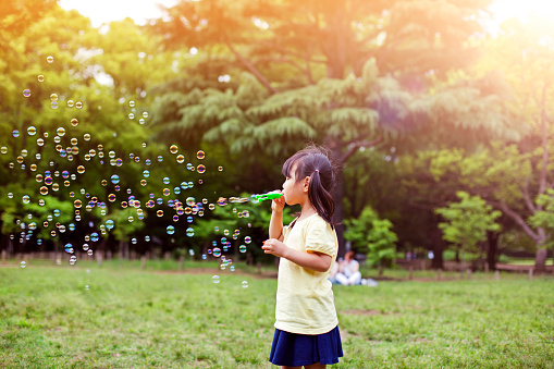 Little girl blowing soap bubbles in park in Tokyo, Japan. Image is taken during Tokyo Istockalypse 2015