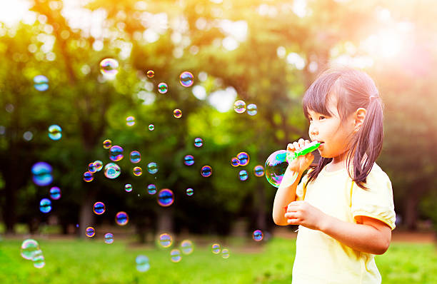 little girl soplando burbujas de jabón - bubble wand bubble child playful fotografías e imágenes de stock