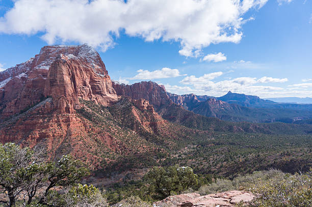 A view of Kolob Canyons in Zion National Park, Utah. A light snow is visible atop the mountains, and the mountains stretch off into the distance.
