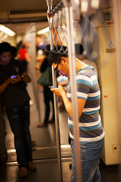 utilisant un iphone de métro mrt - editorial iphone train city photos et images de collection