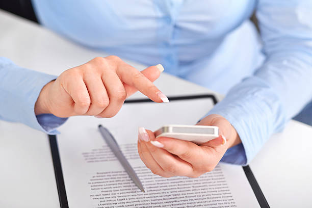istock Young woman working with a mobile phone above the contract 488652929