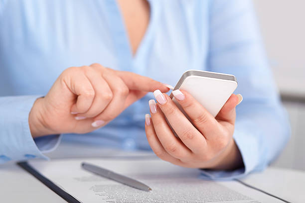 istock Young woman working with a mobile phone above the contract 488652941