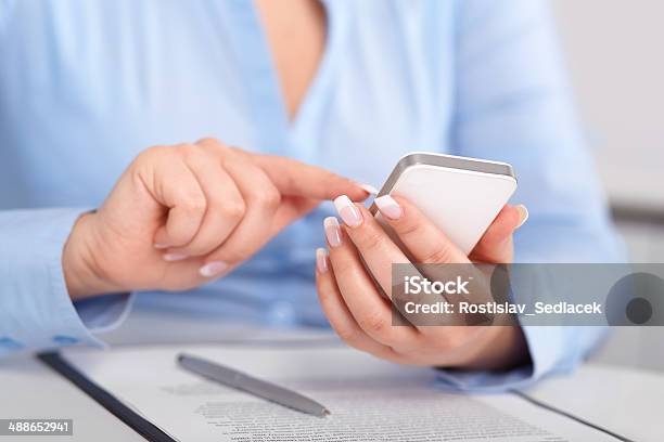 Young Woman Working With A Mobile Phone Above The Contract Stock Photo - Download Image Now