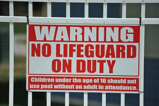 Warning No Lifeguard on Duty Sign on a swimming pool fence