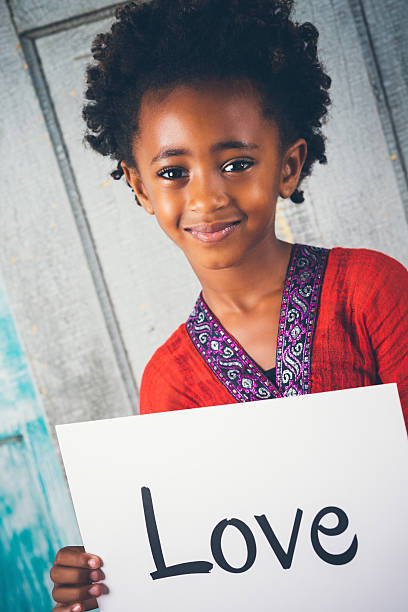 istock Elementary age Ethiopian girl holding LOVE sign 488660542