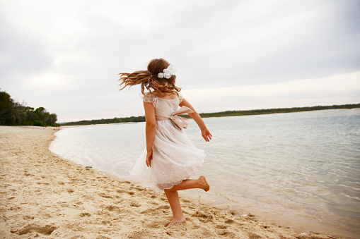 Little girl spins and twirls in a cricle at the beach.