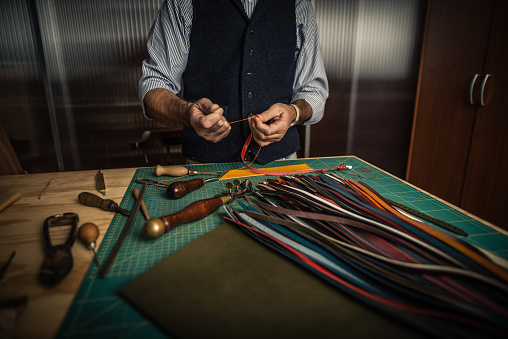 Close up shoot of an artisan working with leather in his laboratory.