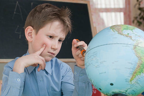 O MENINO sério estudos o mundo - fotografia de stock