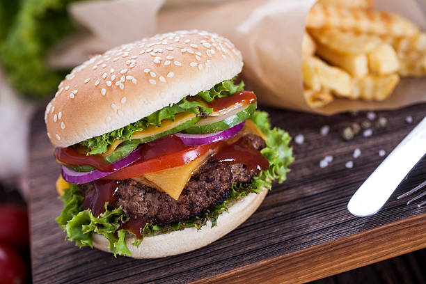 istock Beef burgers on a wooden board with chips and spices 488672808