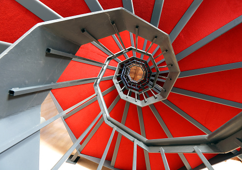 long spiral staircase with red carpet in a modern building
