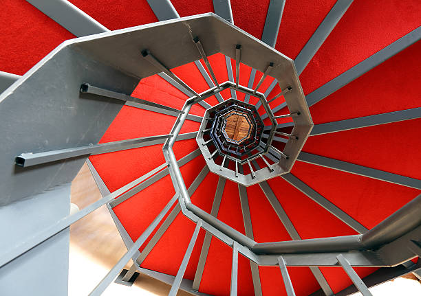 винтовая лестница с красной ковровой дорожке в современном здании - carpet iron стоковые фото и изображения