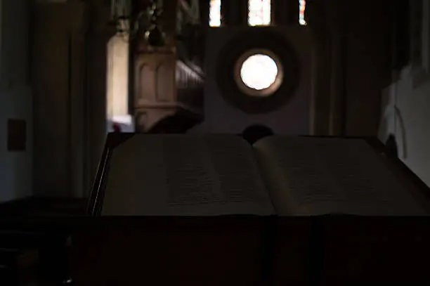 Bible opened in a church with backlight from rose-window.