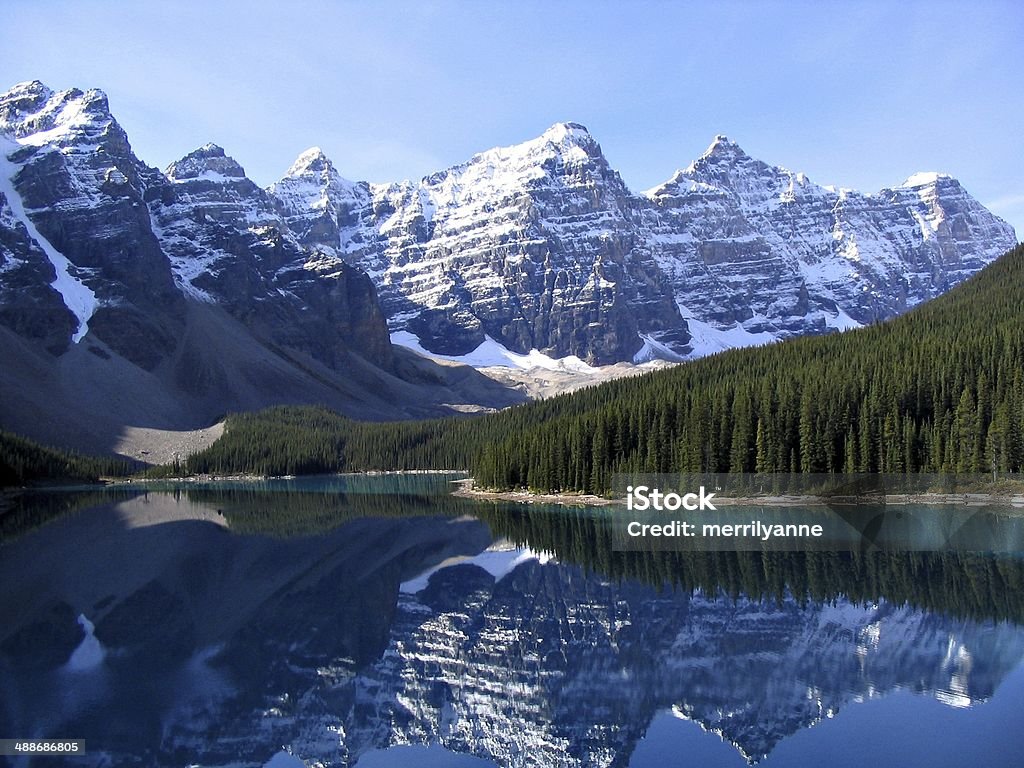 Moraine Lake, near Banff and Jasper Alberta, Canada Stunning photo of Moraine Lake, Alberta, Canada, on a clear bright sunny day with white clouds and blue sky.  The lake is a stunning blue colour, and surrounded by trees and snow capped mountains. Alberta Stock Photo