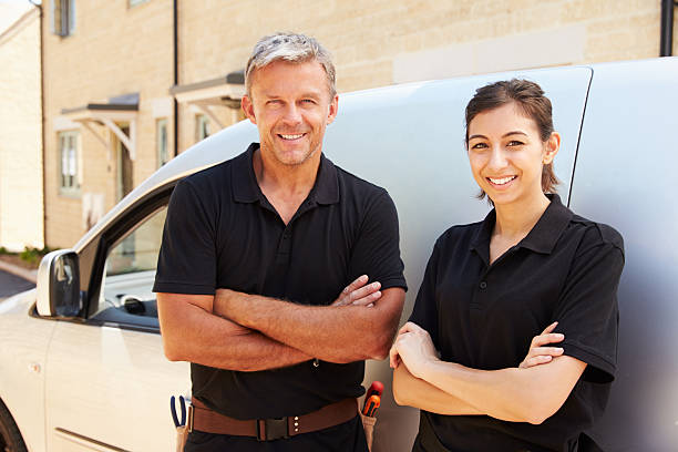 istock Male and female trade workers standing by a van 488687756