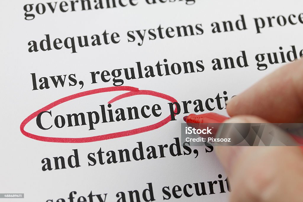 Word Compliance Circled by Hand with Red Pen Red Pen making a circle around the word compliance in a body of text Conformity Stock Photo