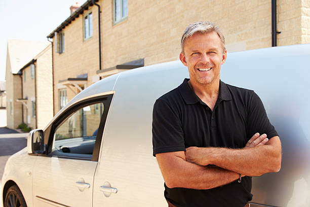 Portrait of middle aged tradesman standing by his van Portrait of middle aged tradesman standing by his van blue collar worker photos stock pictures, royalty-free photos & images