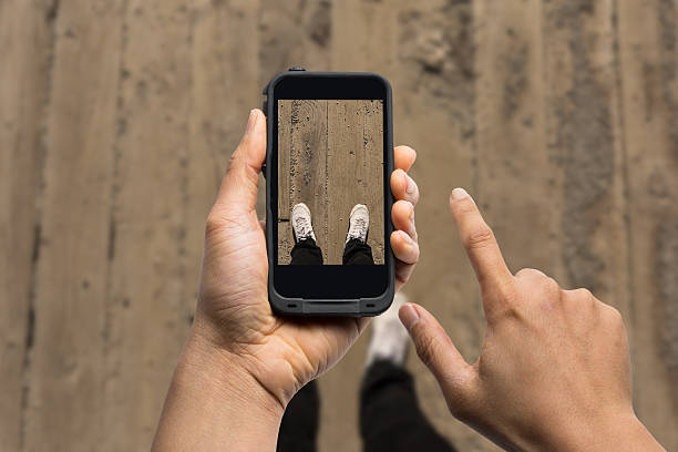 men using smart phone taking photo of his feet on wooden bridge