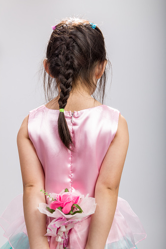 Rear view of cute Asian girl holding flower.