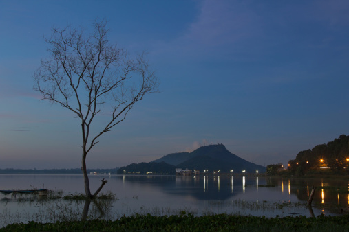 Sunrise over dam with dead trees , at Thailand