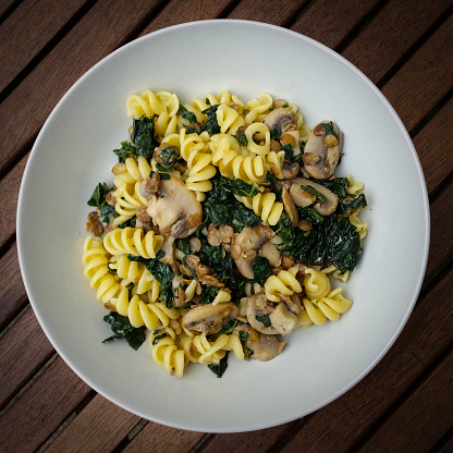 A lunch bowl of pasta with cavolo nero, mushrooms, lentils and stirred through with cream cheese.  Overhead shot with a vignette a square Instagram style