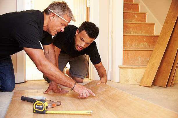 two men laying wood panel flooring in a house - werkvloer stockfoto's en -beelden