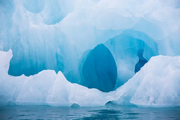 Blue iceberg floating in the Hornsund Spitzbergen. Blue ice is very old ice, which was under pressure by the glacier. The cloudy, fogy weather is typical for the north and the light show the wide spectrum of the blue colors.