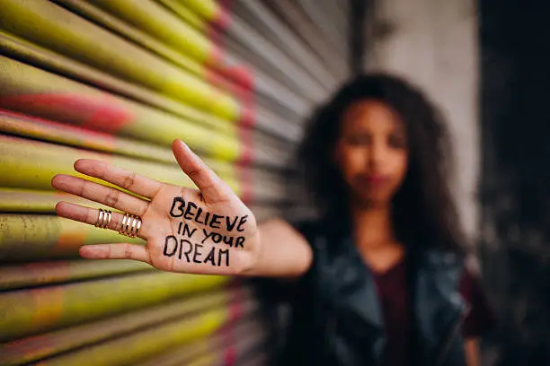Closeup of the hand of an African American girl with an inspirational message written on it in permanent marker