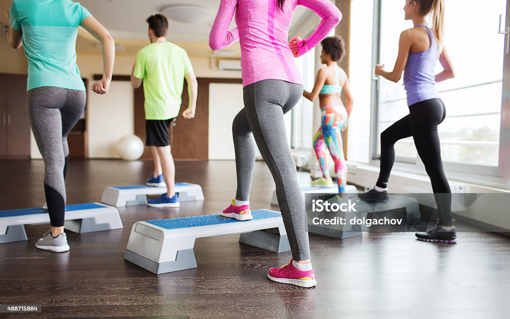 close up of people working out with steppers in gym fitness, sport, training, aerobics and people concept - close up of people working out with steppers in gym from back Step Aerobics Stock Photo