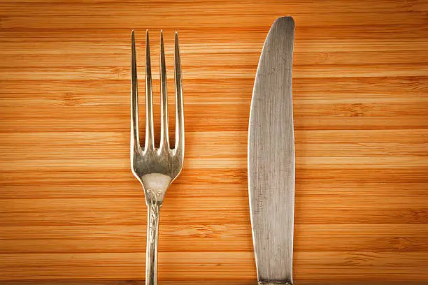 Vintage fork and knife on wooden chopping board