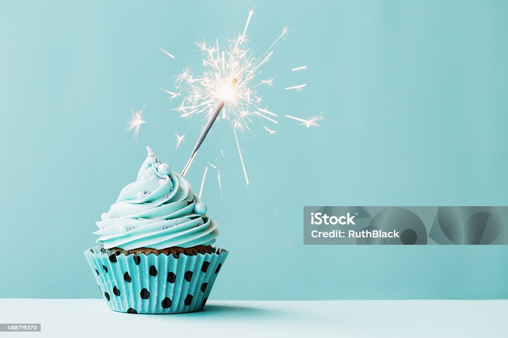 Cupcake with sparkler Cupcake with sparkler against blue Birthday Stock Photo