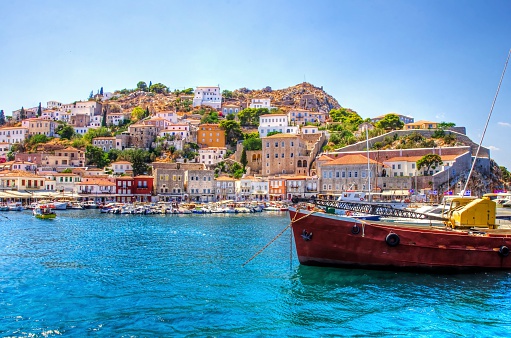 A view of the beautiful Greek island, Hydra. There is a fishing boat on the foreground and some local architecture on the background. The view is from the sea as the cruise ship embarked in Hydra.