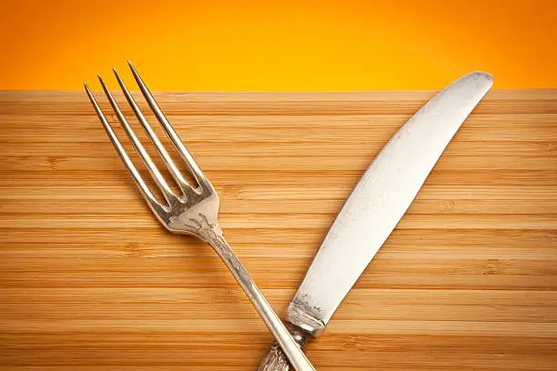 Vintage fork and knife on wooden chopping board