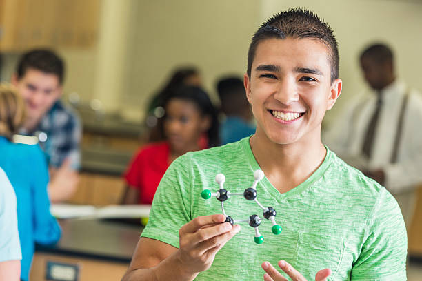 high school student holding molecule модели в его науке класс - multi ethnic group concentration classroom latin american and hispanic ethnicity стоковые фото и изображения