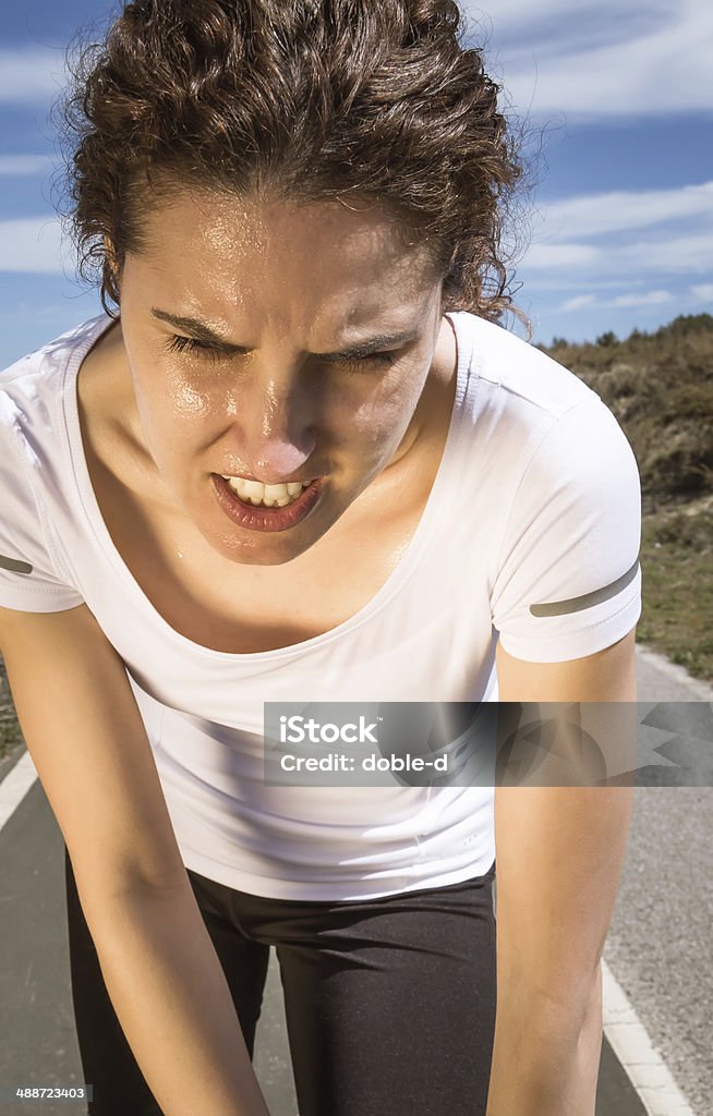 Tired runner girl sweating after running with sun Portrait of tired runner girl sweating after running hard in a outdoor training on sunny day Active Lifestyle Stock Photo