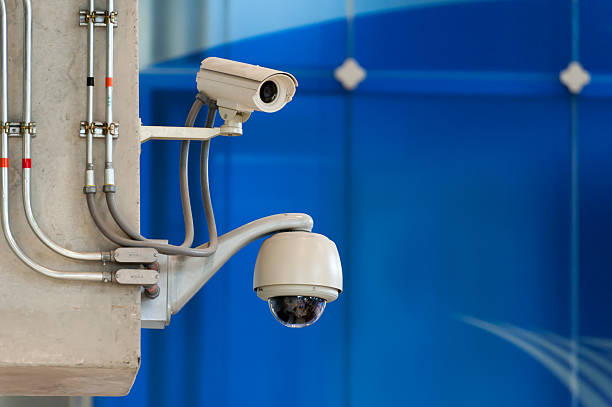 istock 3 CCTV camera or surveillance operating on blue wall bakcground 488725787