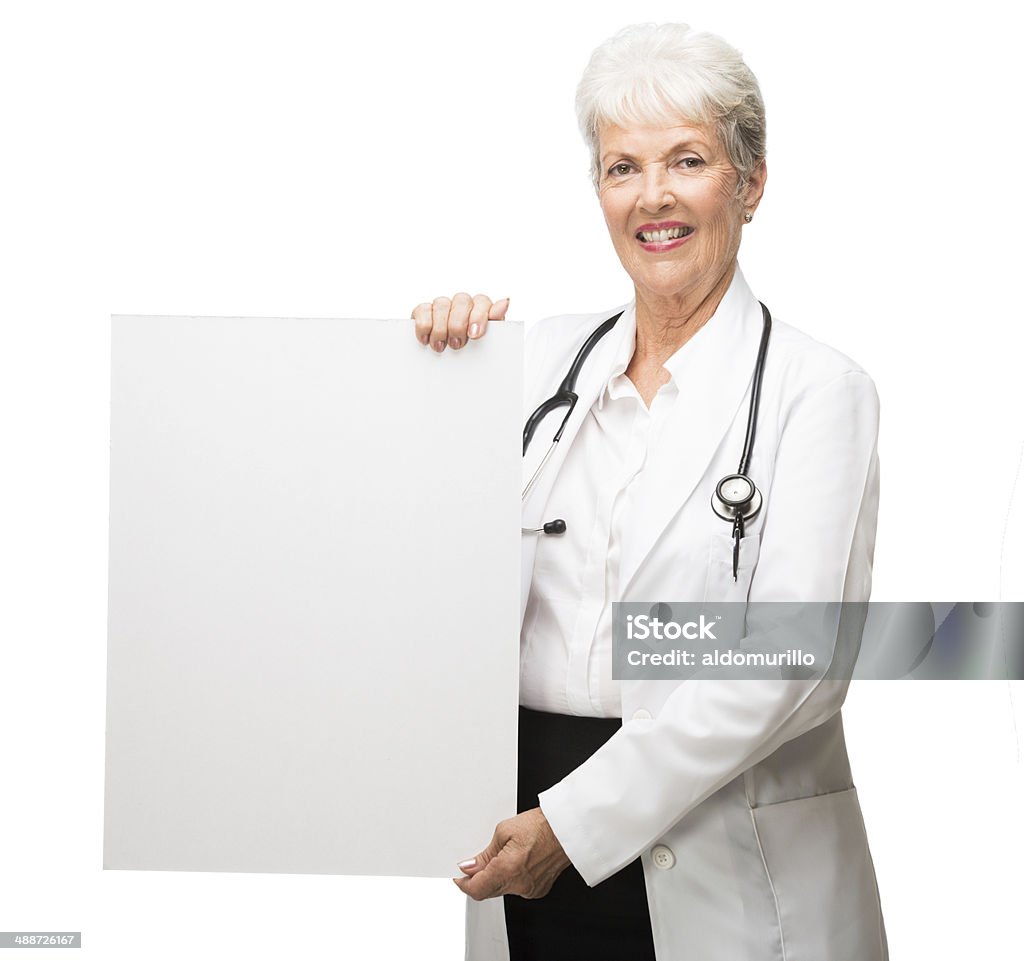 Cheerful latin doctor holding a sign A half body shot of a cheerful latin doctor holding a sign. Isolated on a white background. 70-79 Years Stock Photo