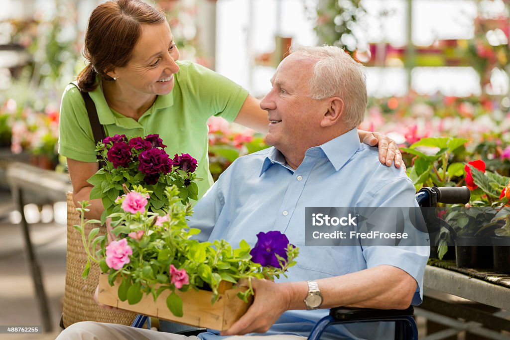 caregiver and senior man at a garden center assisted living Assistance living – caregiver and senior man at a garden center Gardening Stock Photo