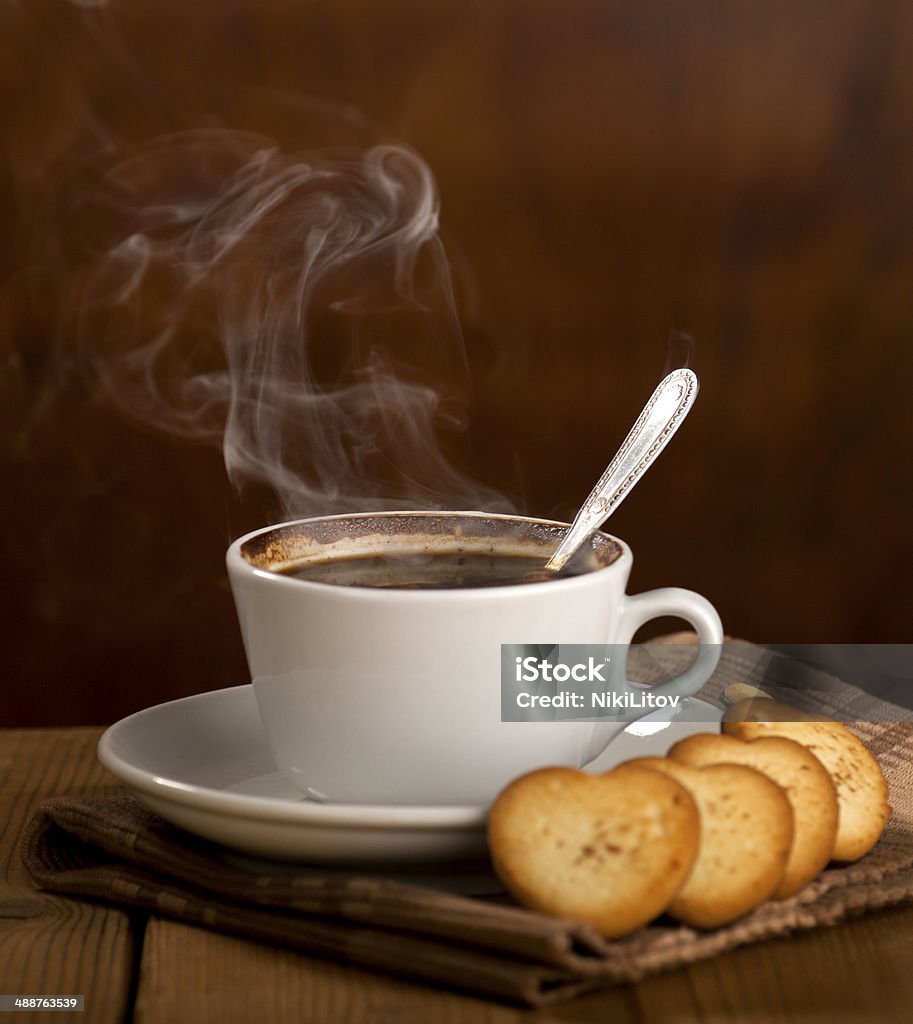 Sweet Coffee Morning White cup with coffee hot chocolate cappuccino latte or mochaccino and cookies in a heart shape on brown pad and wooden background. Cookie Stock Photo