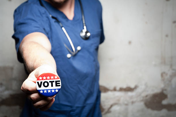Health care vote A stock photo of a health care worker suggesting to vote doctor badge stock pictures, royalty-free photos & images