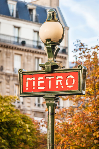 Paris, France. October, 2022. Famous subway signboard in Paris against the background of a blooming tree.