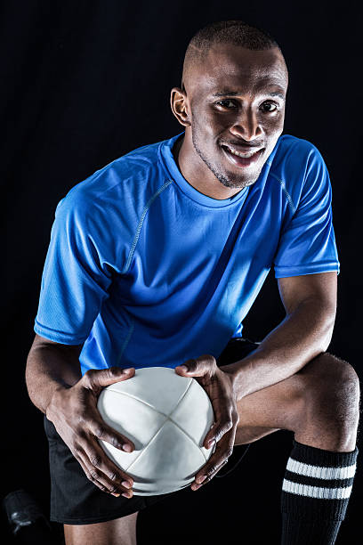 istock Portrait of rugby player with ball smiling while kneeling 488765376