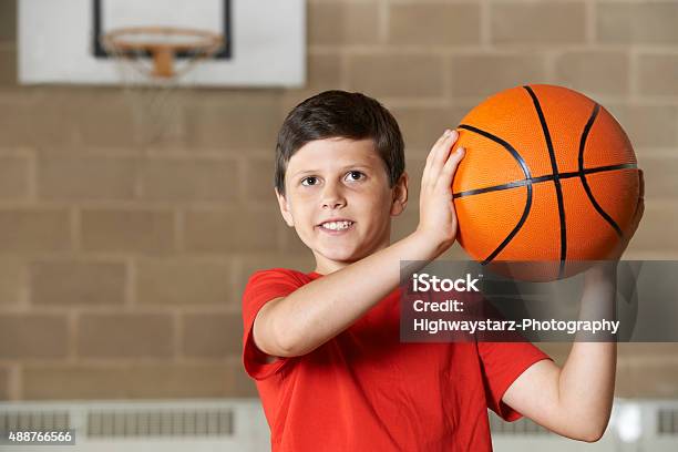 Boy Shooting Durante El Partido En La Escuela Gimnasio De Básquetbol Foto de stock y más banco de imágenes de Niños