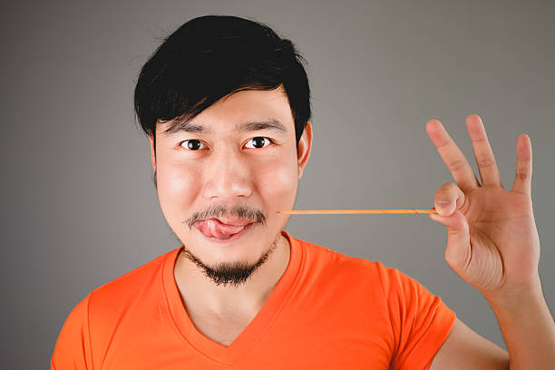 Asian man is eating BBQ skewers.