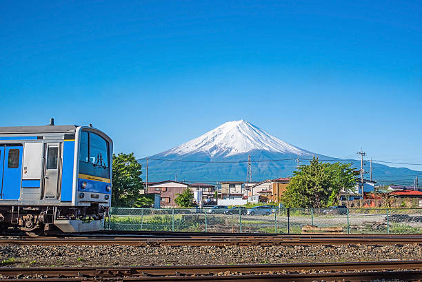 Blue train on railroad tracks with Mount Fuji stock photo