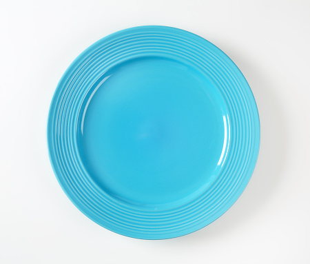 Blue glazed dinner plate with embossed concentric rings on the edge